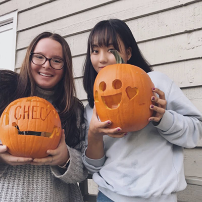 Korean Buddy Program pumpkin carving event - two buddies pictured holding up carved pumpkins