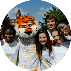 A group of students smile while posing with Aubie.