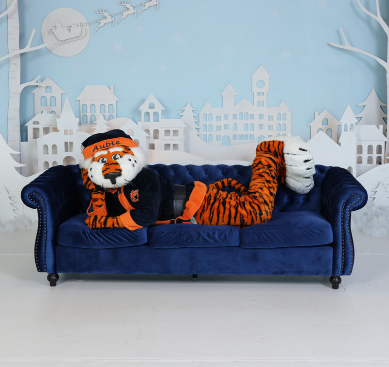 Aubie Claus on a couch surrounded by Christmas cutout decorations