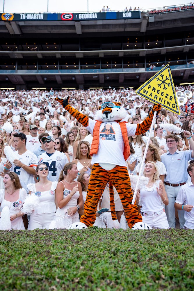 Aubie in front of the crowd at a football game holding the Freeze Warning sign created by the Aubie Committee