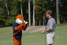 Aubie performs caddy duties at the golf tournament