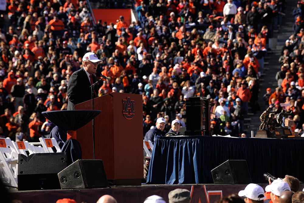 President Jay Gogue stands at a podium on Pat Dye Field at Jordan-Hare Stadium as a crowded stadium looks on during the celebration of Auburn’s 2010 football national championship.