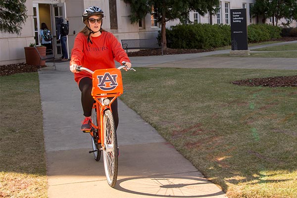 A student rides an Auburn-branded bicycle from the on-campus bike share program.