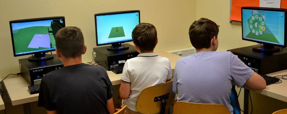 Three boys using computer simulation games on computers.