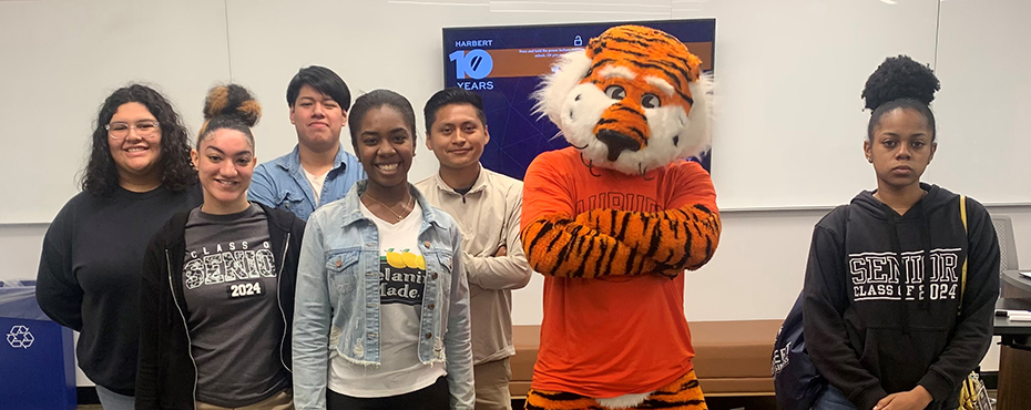 A small group of male and female students stand with Aubie for a picture