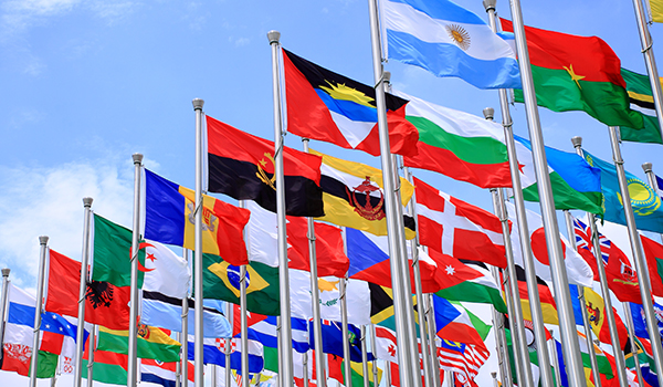 Flag poles with flags from around the world against a blue sky