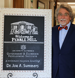 Joe Sumners and a sign that reads Welcome to Pebble Hill, University Outreach, Government and Economic Institute, A retirement reception honoring, Dr. Joe A Sumners