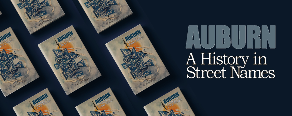 An aerial view showing several copies of the book Auburn: A History in Street Names. Books are in rows along a dark blue background next to typography that displays the book title.