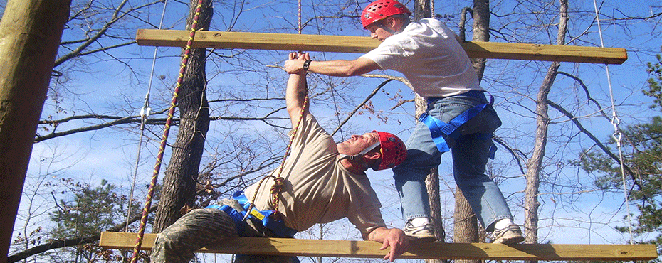 People climb a ladder at the challenge course.