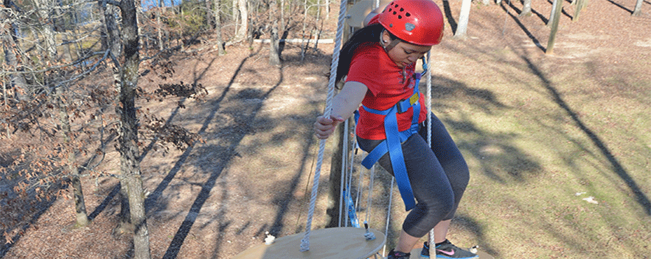 A child does the ropes course at the challenge course.