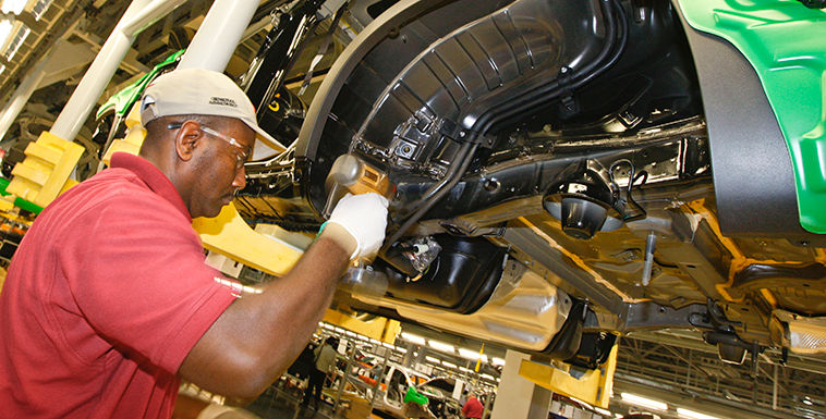 A factory worker at the Hyundai plant installs new parts on a car.
