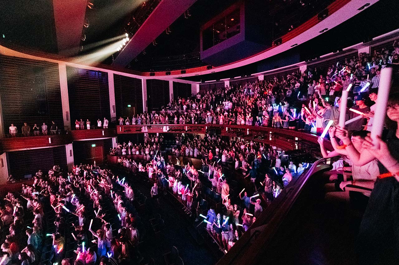 A packed auditorium with colored lights