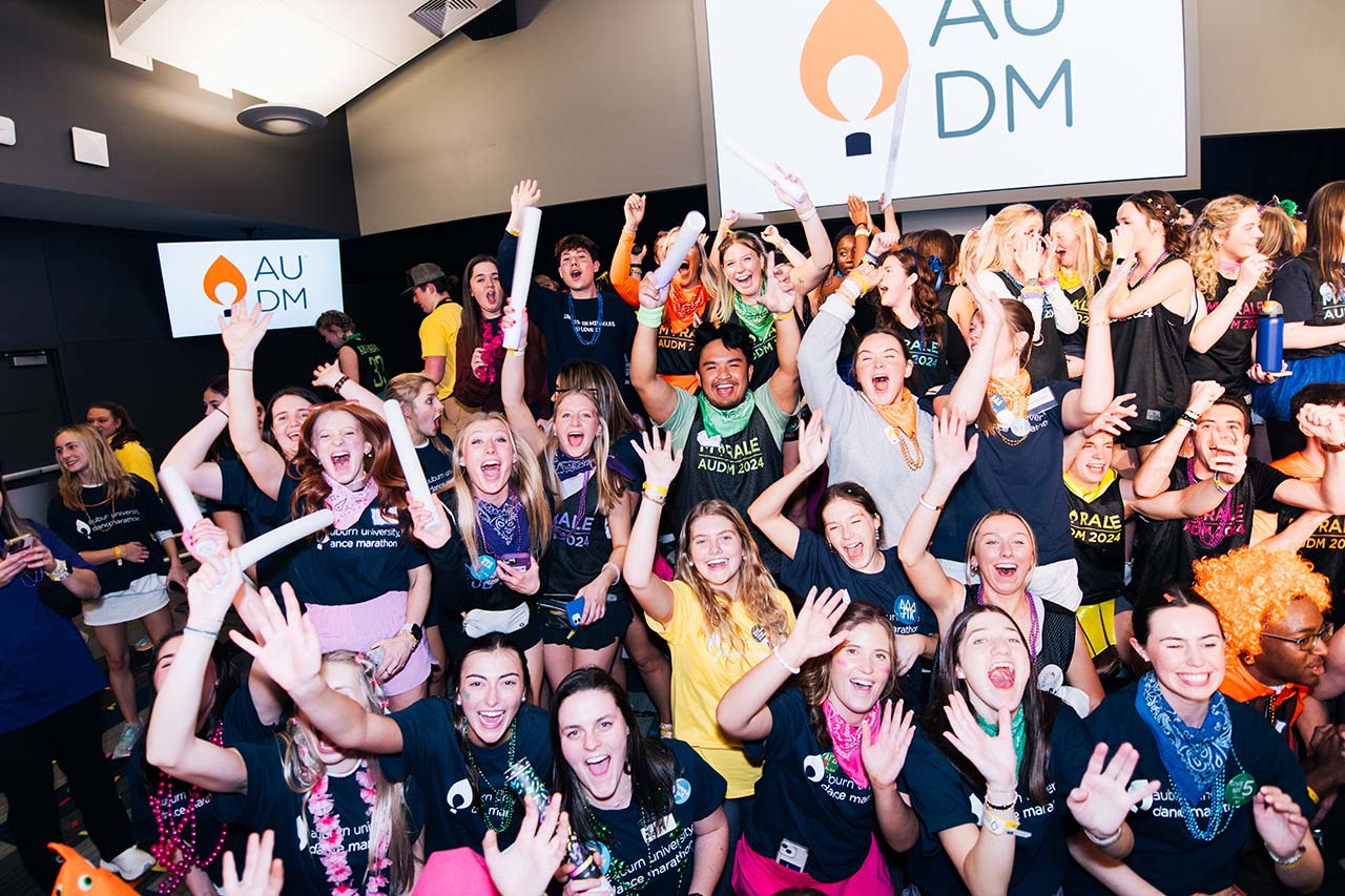 A group of students smiling and waving
