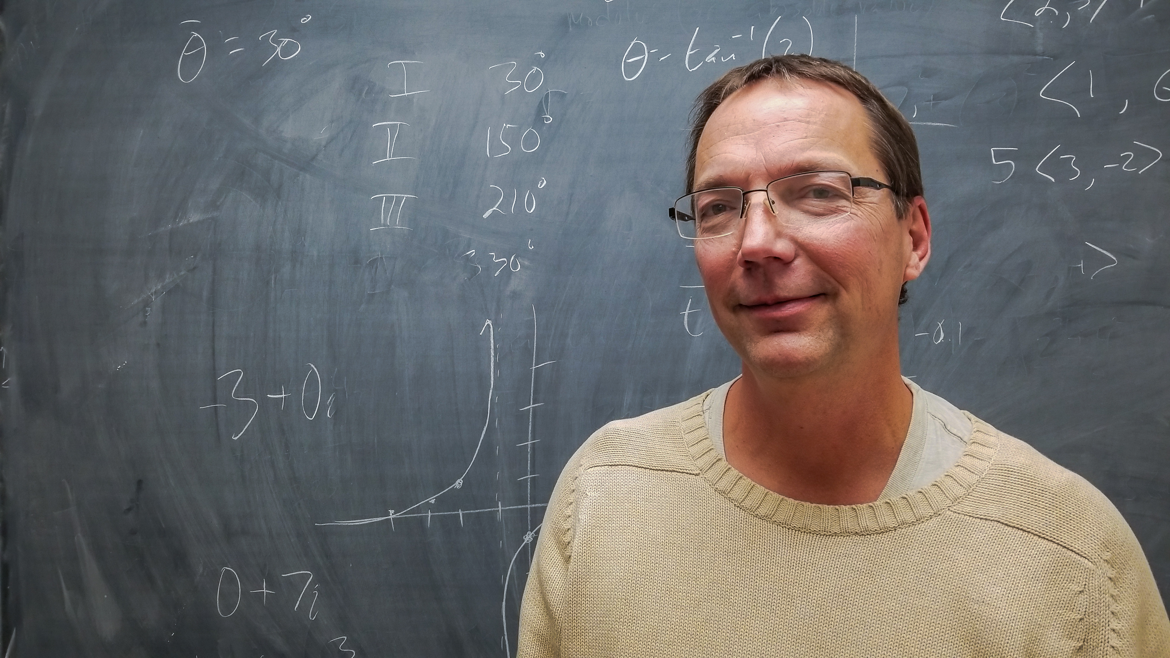 Lecturer Eric Harshbarger in front of a chalkboard