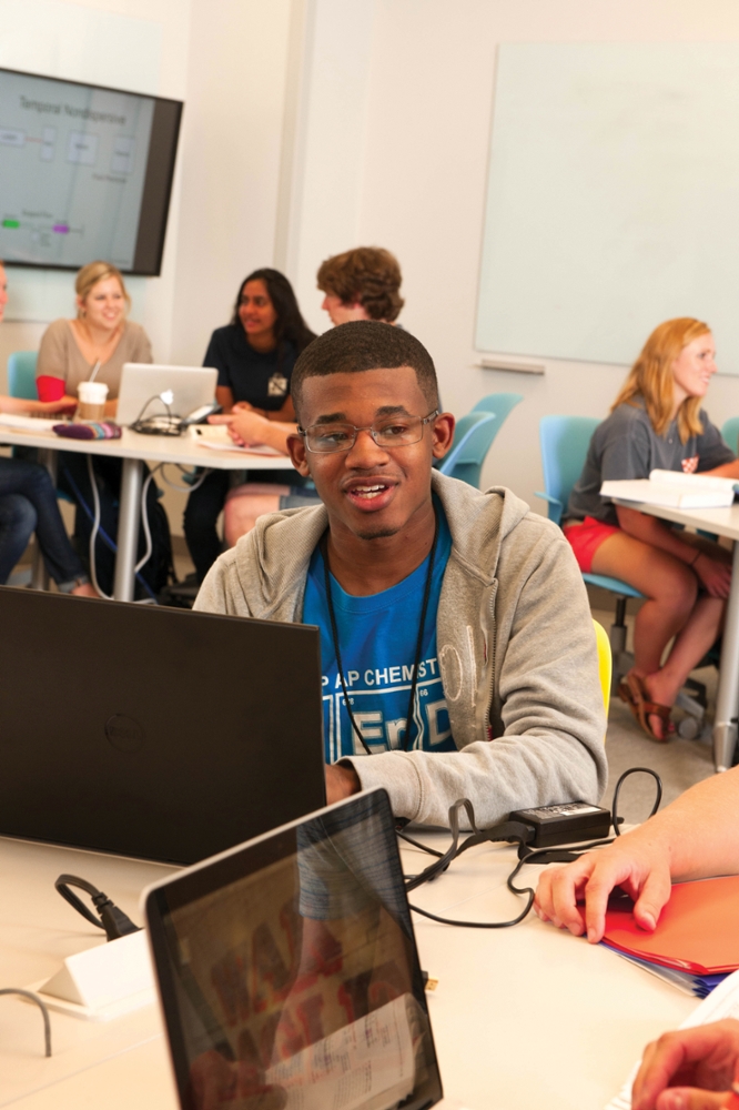 A student uses his laptop while seated at a hexagonal table in the EASL classroom