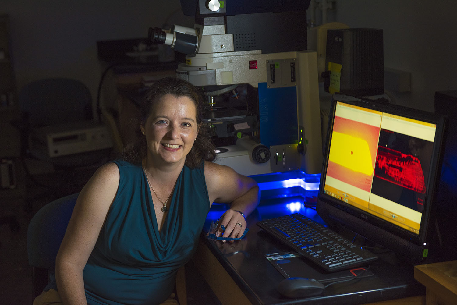 Anne Gorden smiling for a photo while sitting beside a computer in her lab