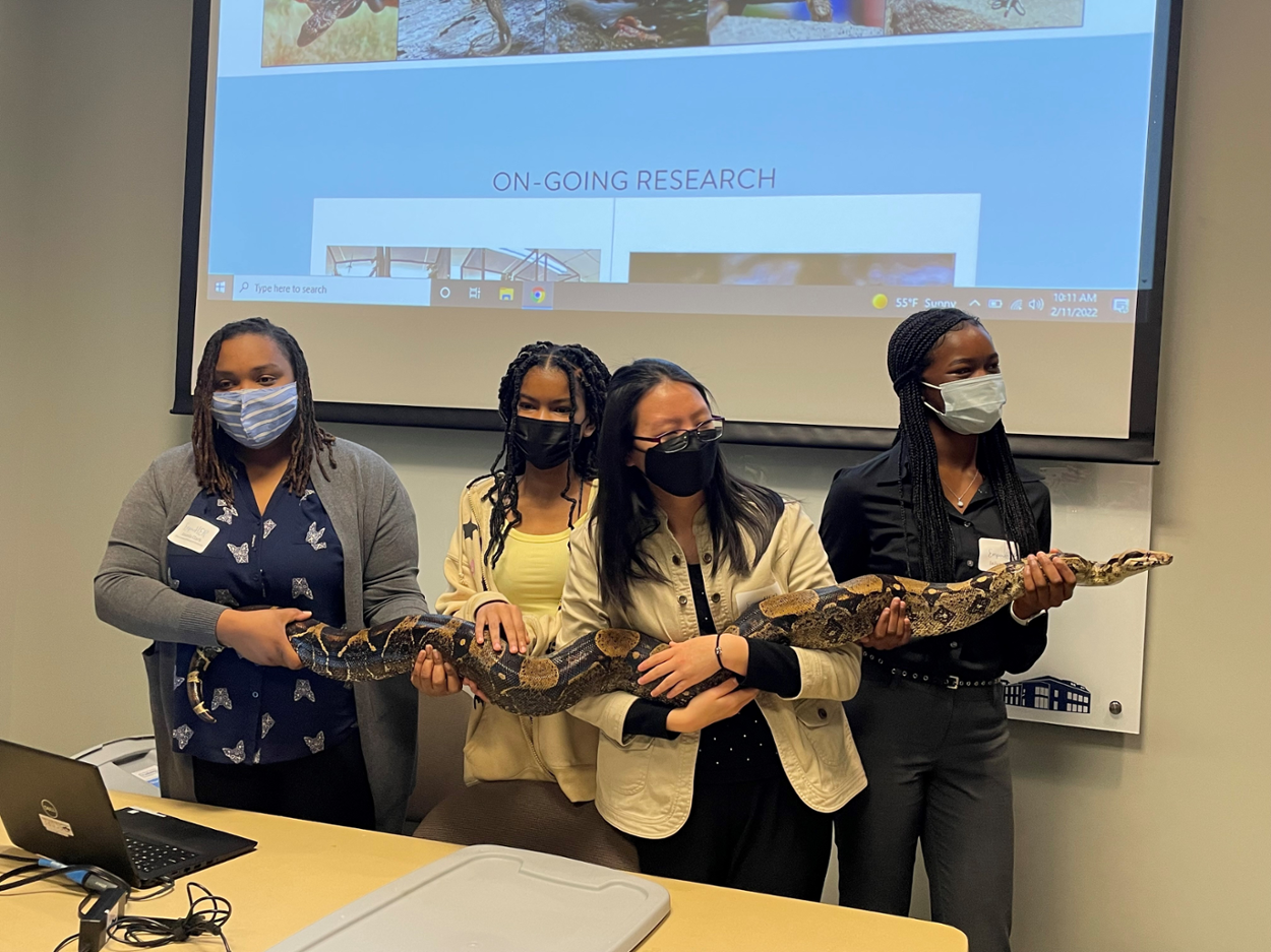 Students holding a large snake during a presentation