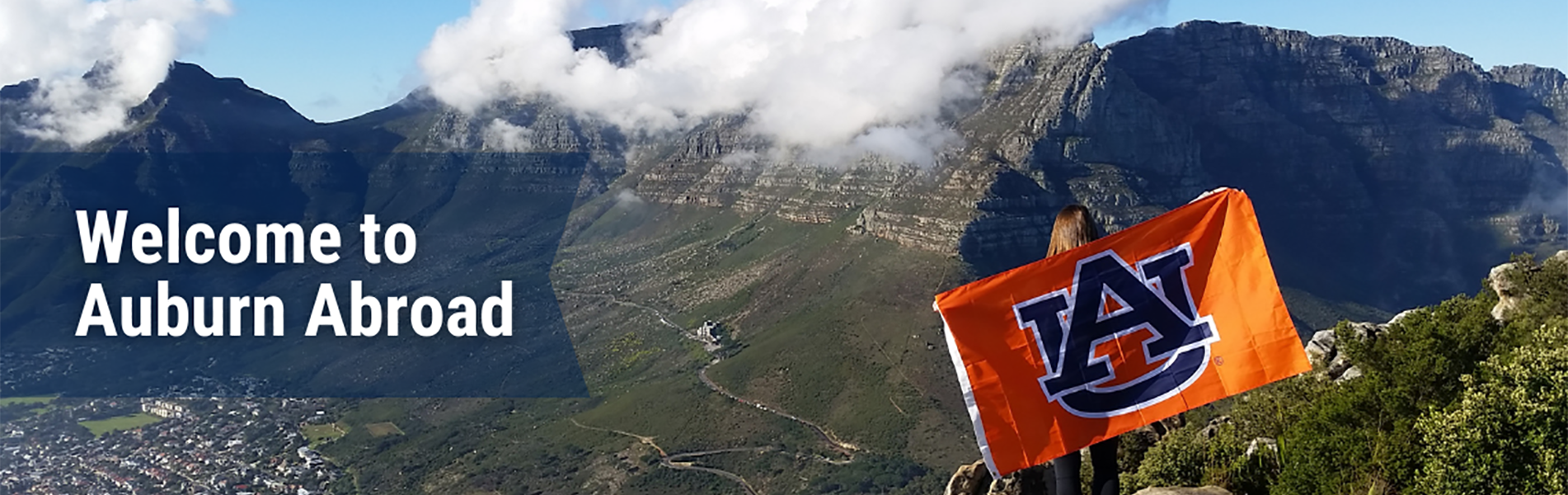 Welcome to Auburn Abroad - image of a student abroad in mountains holding an Auburn flag