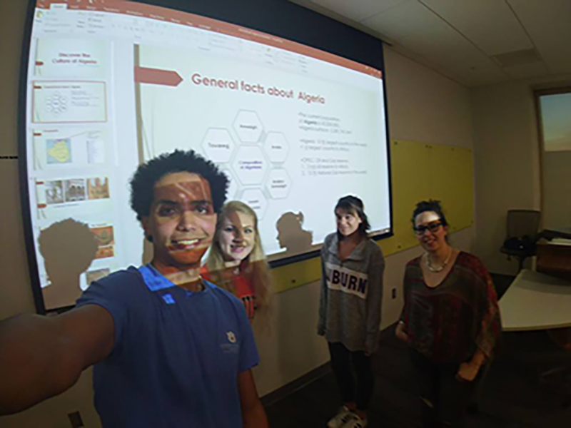 Image of students in Arabic language class posing for a selfie in light of projector