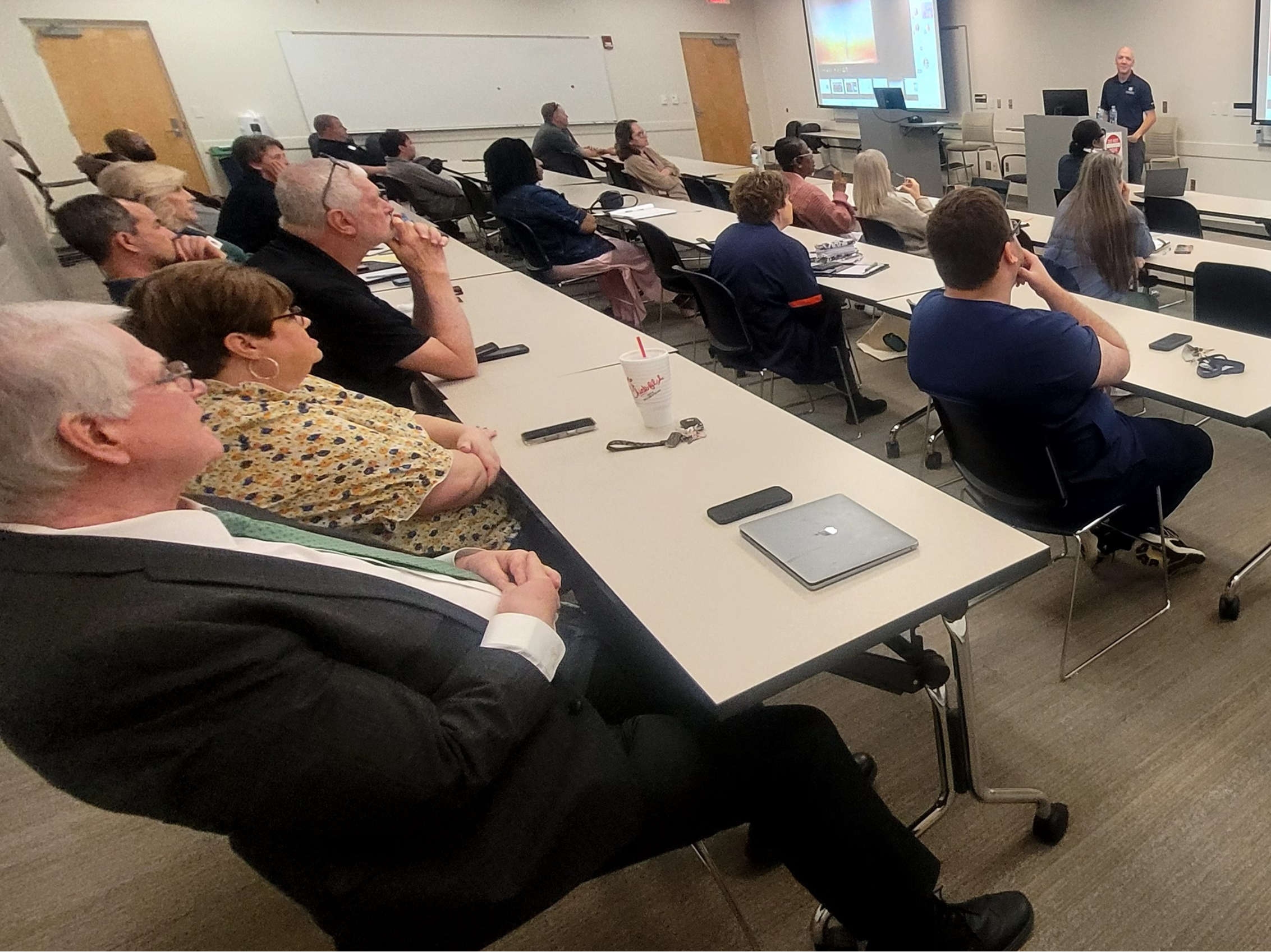 man speaking to room full of people