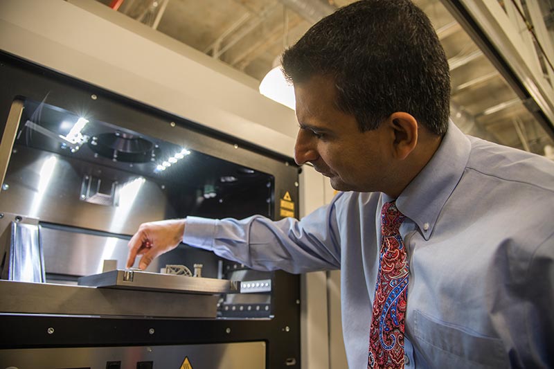 A professor examines pieces created with a 3d printer