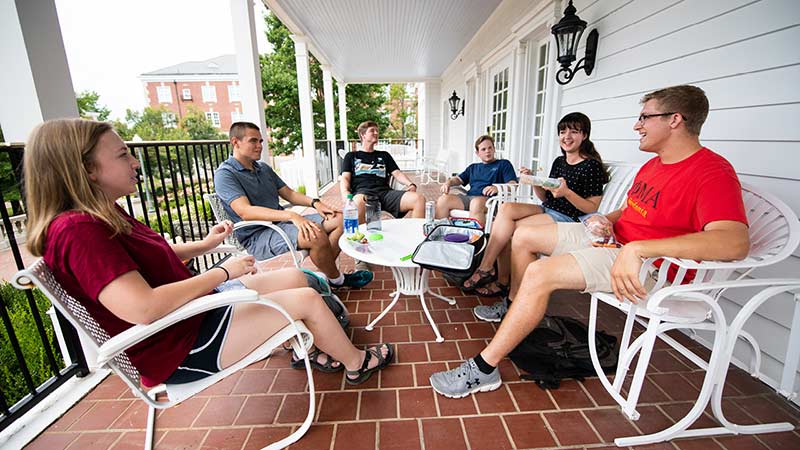 Students sit on a patio and talk