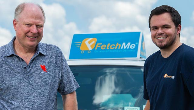 Two men stand next to car with the Fetch Me sign