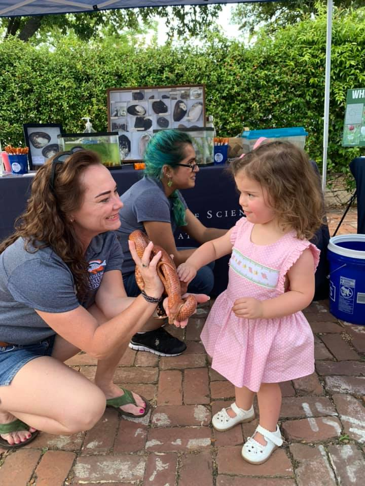 Toni with a young girl during an outreach event learning about native snakes