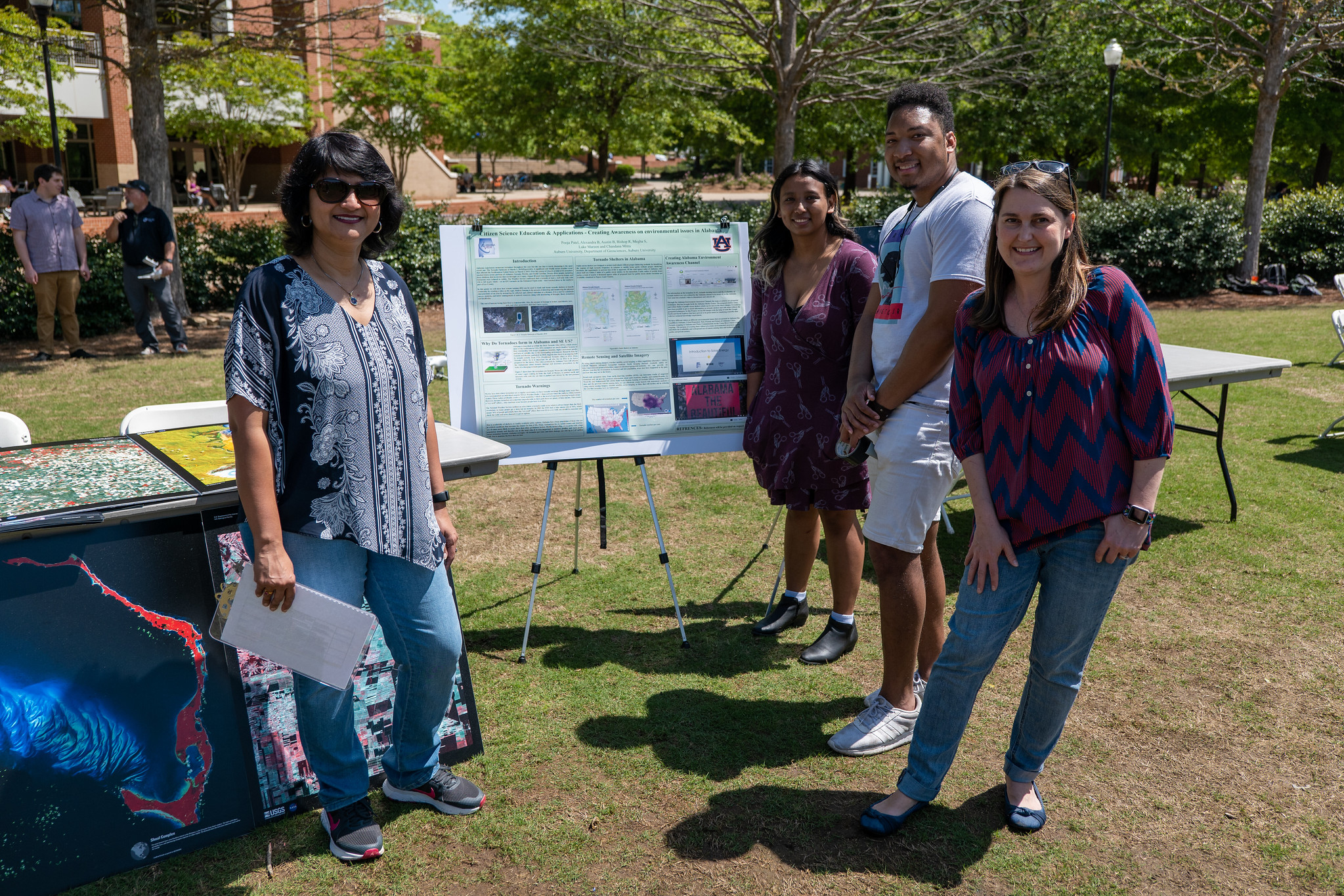 a group of researchers stands alongside a poster outdoors
