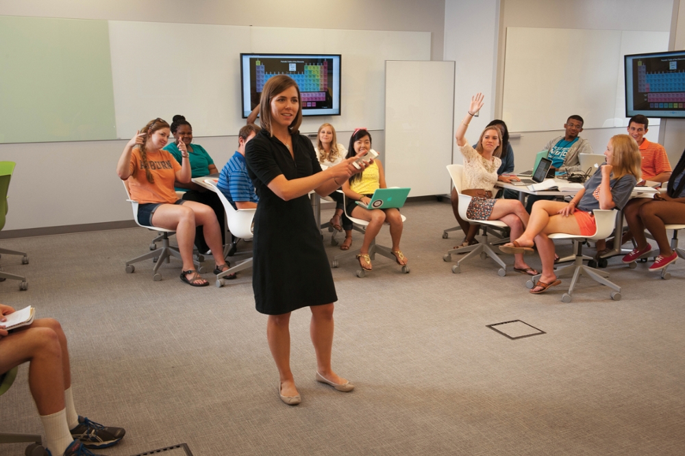 A student speaks in the middle of the EASL classroom surrounded by students seated at tables