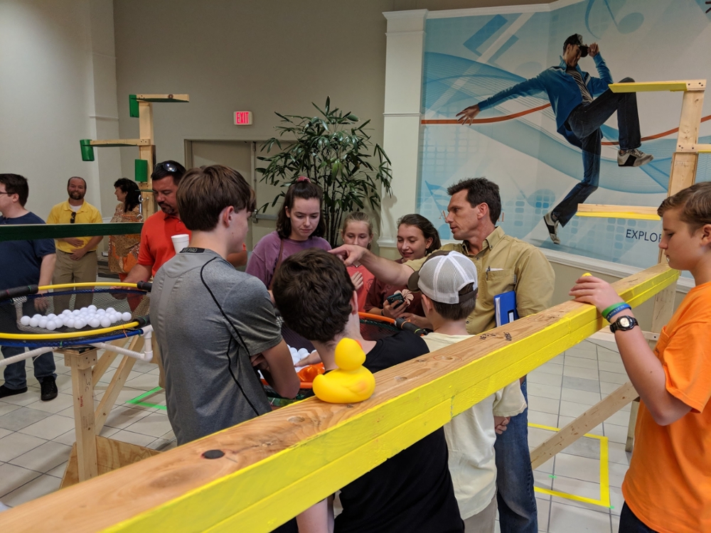 Image of students looking at a life-size robotics competition set-up. 