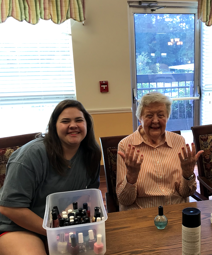 COSAM student helps paint nails at a local retirement home.