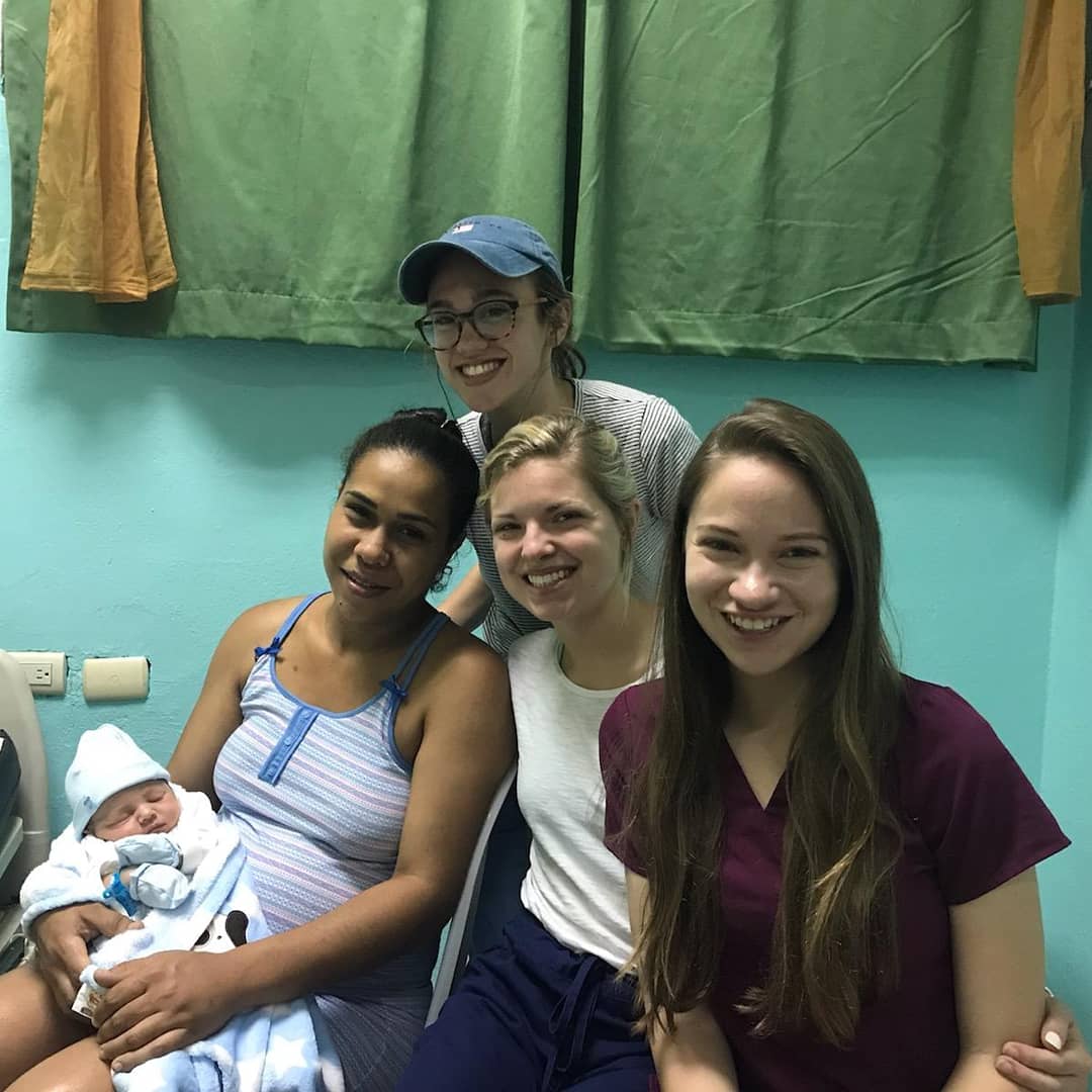 Students shadowing doctors at a hospital in the Dominican Republic pictured with a mother and her two-day old baby.