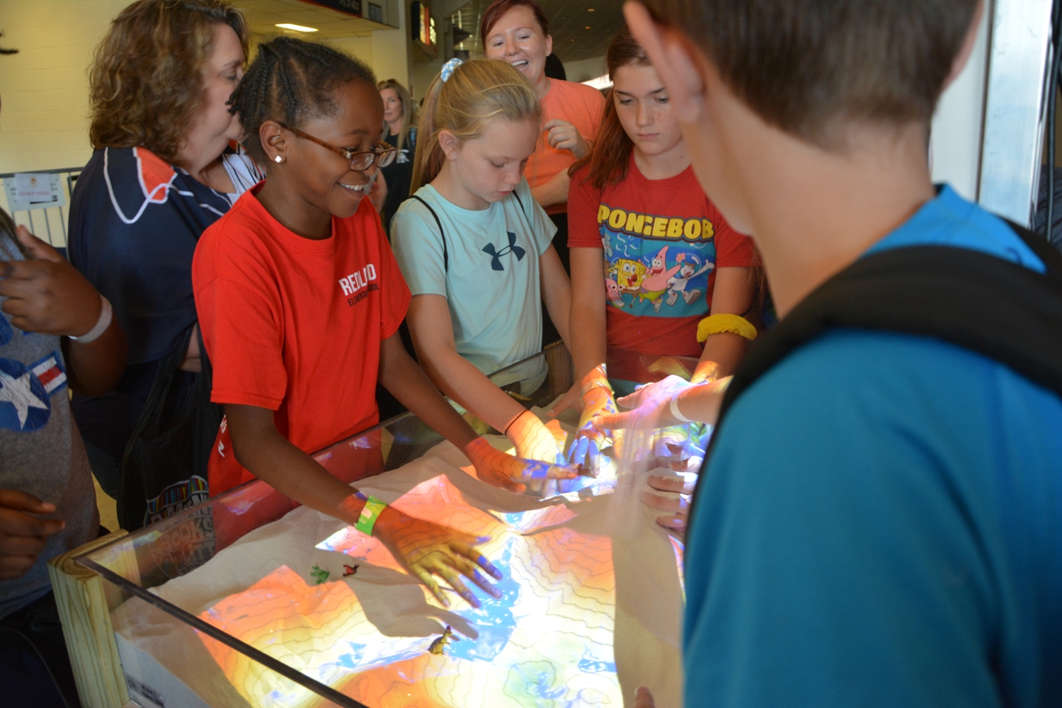 Students learning hands-on through a sandbox with the Department of Geosciences at Destination STEM. 