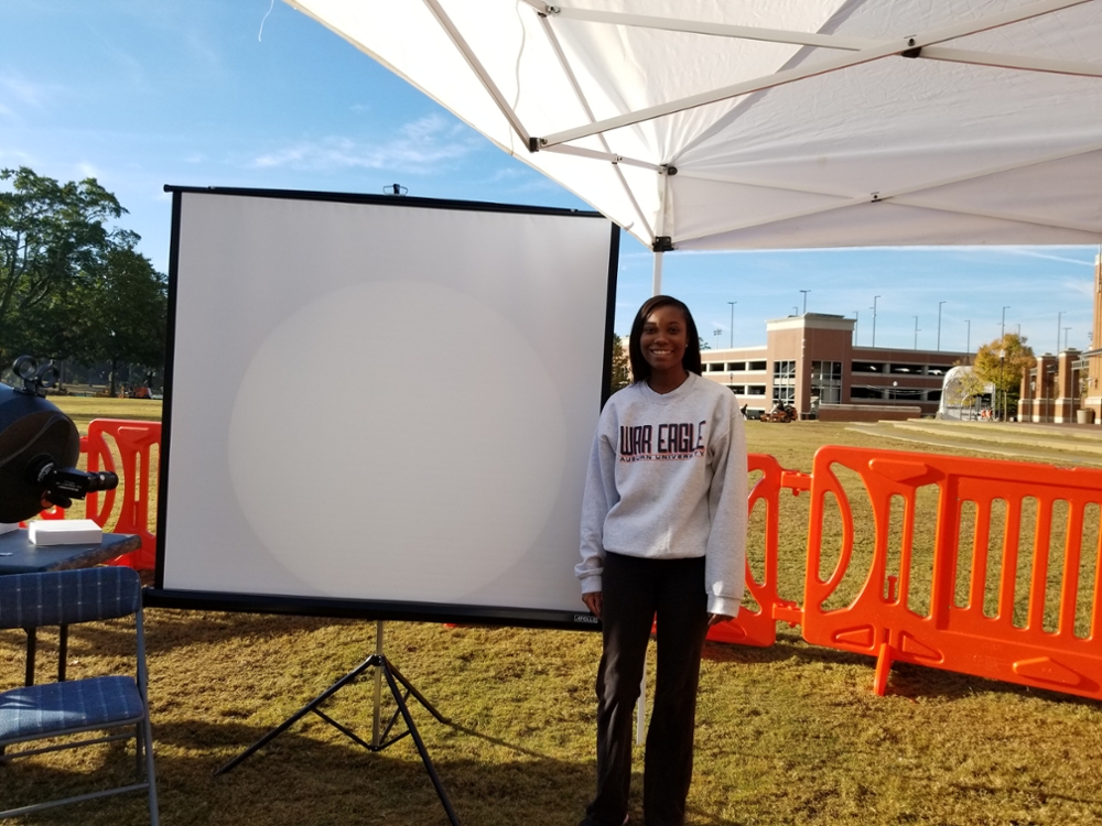 Jaden Jarman stands next to a projected image of the Transit of Mercury. 