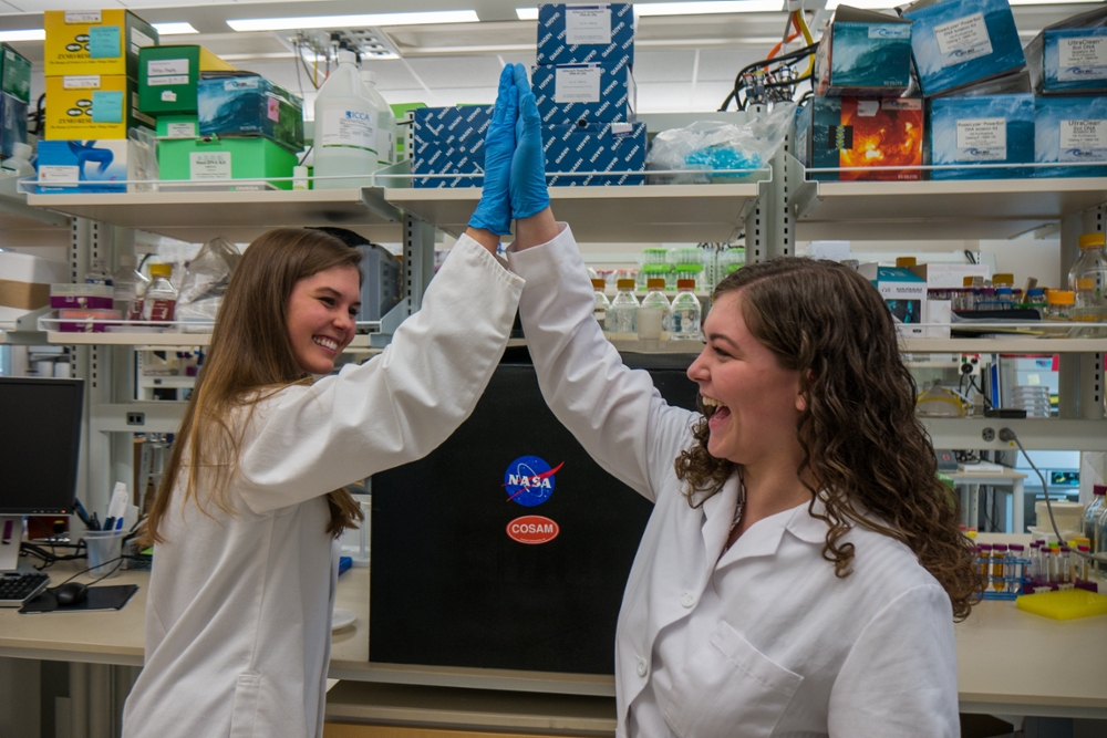Fall 2019 COSAM Graduation Marshal Morgan Sisk and COSAM undergraduate student Natalie Williams celebrate that they created an insulated cover for this piece of equipment for the NASA project. 