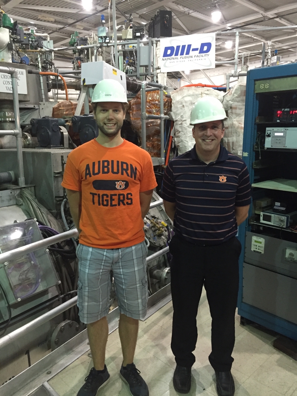 Graduate Student Curtis Johnson (left) and Professor Stuart Loch (right) standing in front of the DIII-D plasma physics experiment located in San Diego, CA.
