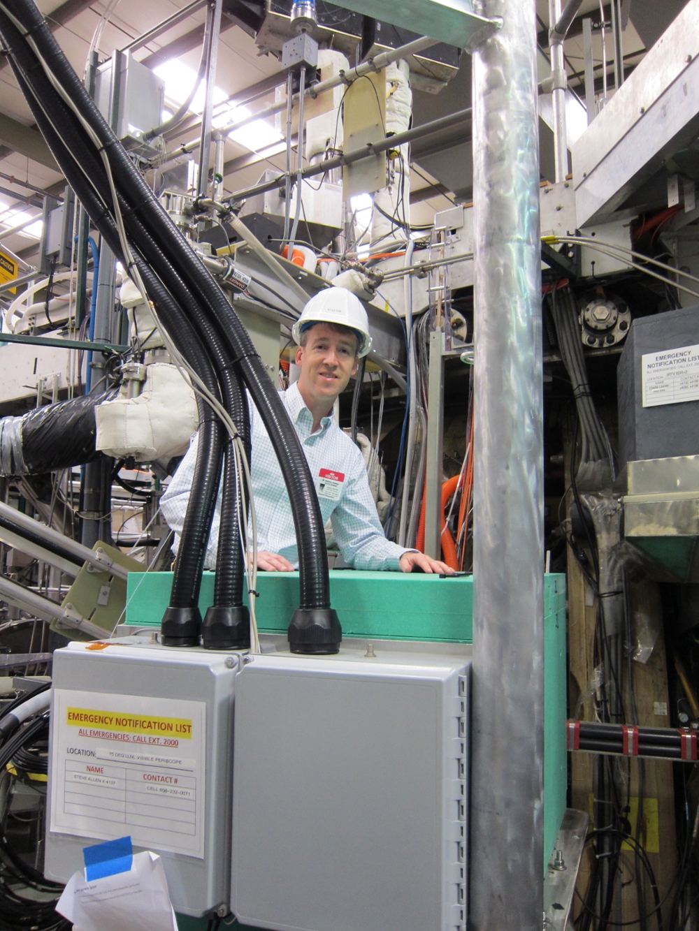 Professor David Ennis next to the shield box housing the UV survey spectrometers in the DIII-D experimental hall.
