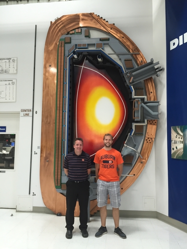 Professor Stuart Loch (left) and Curtis Johnson (right) in front of a full-scale model cross-section of the DIII-D plasma experiment.