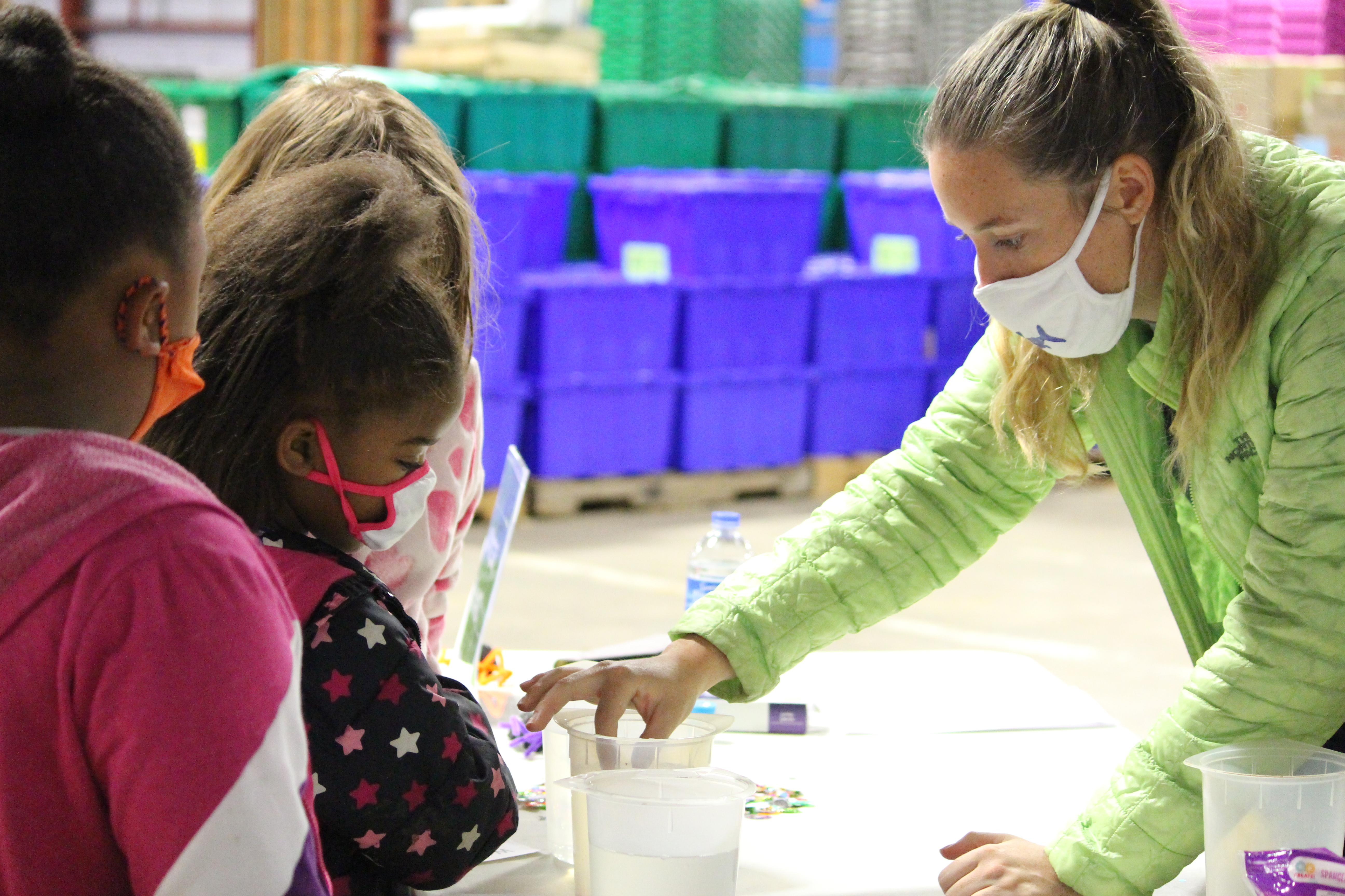 Volunteer showing students an activity with two containers of liquid