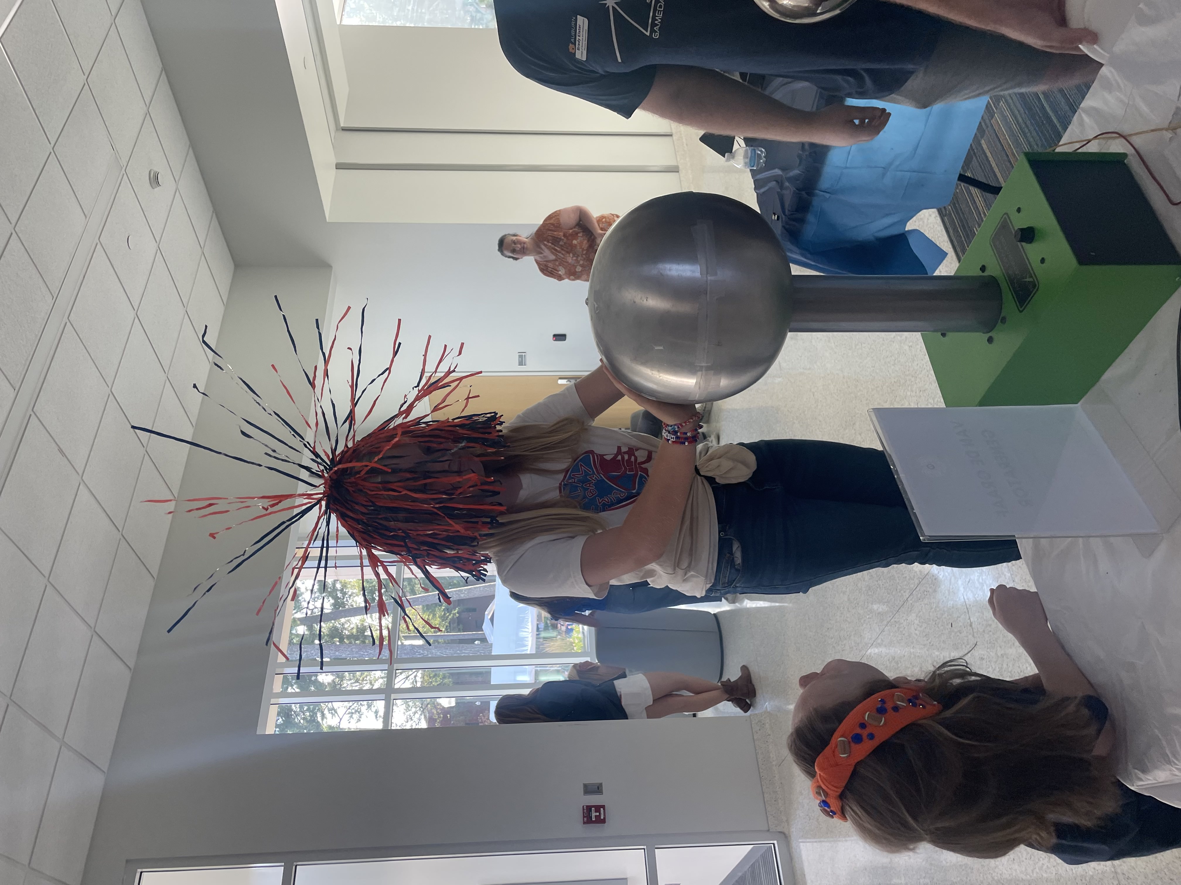 The Van de Graaf generator demonstrates static electricity through a gameday shaker. This device produces high electrical potential.