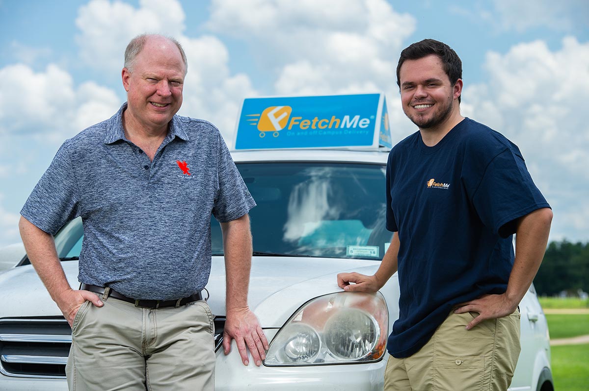 Dave Ketchen and Harrison Evola stand in front of a delivery vehicle.