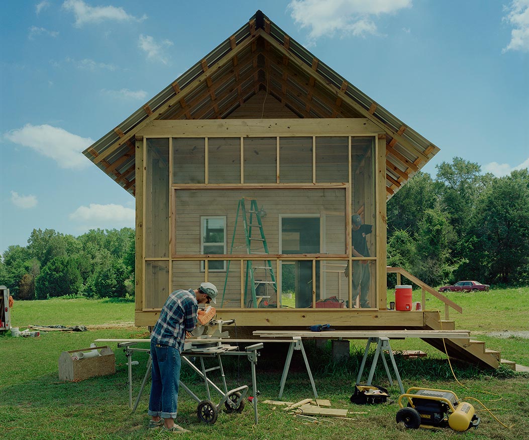 A student works in front of a new home construction.