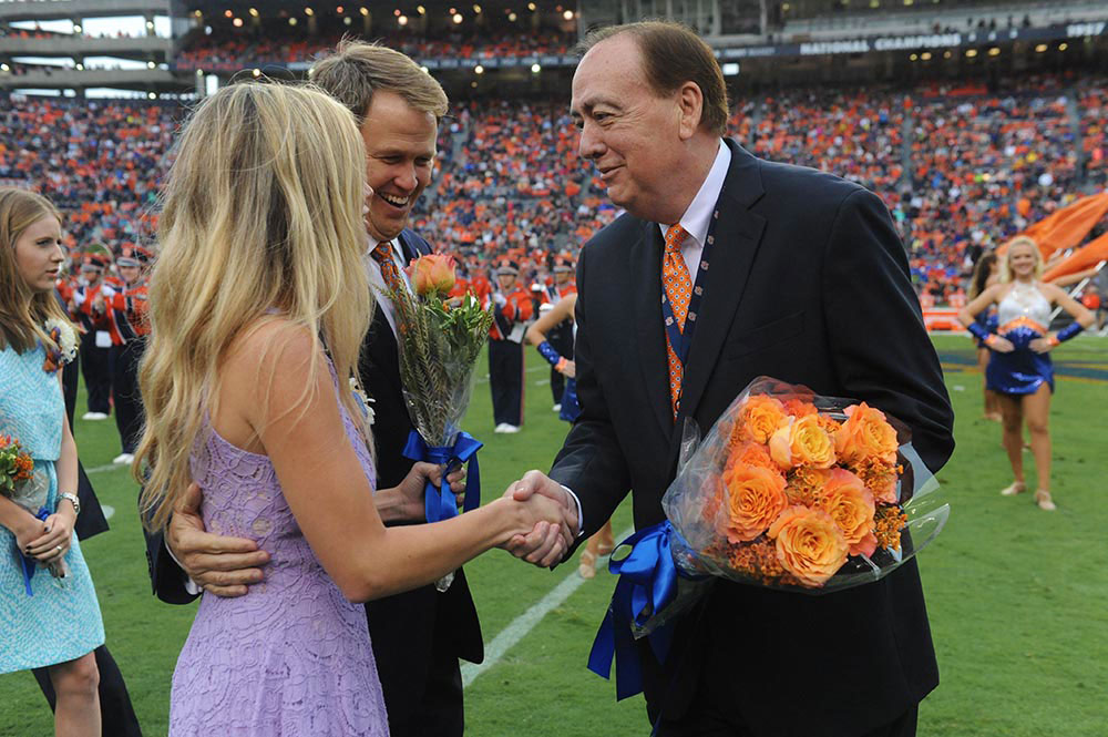 Jay Gogue stands on the field at Jordan-Hare stadium as he prepares to present a bouquet of flowers to Auburn’s 2015 Miss Homecoming.