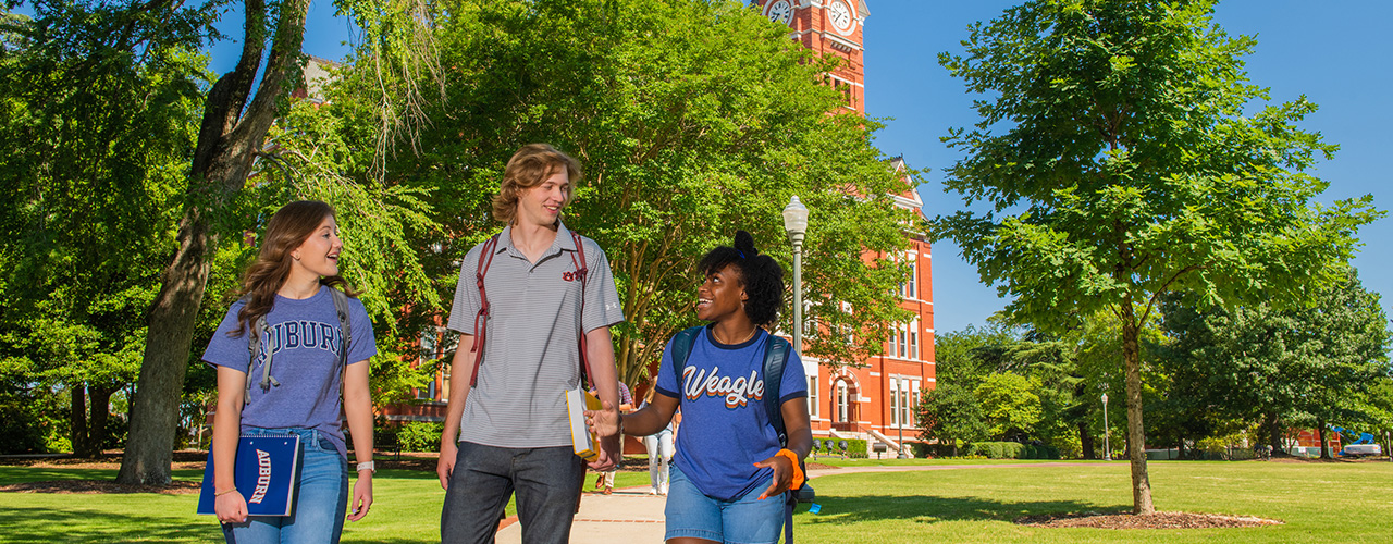 Three students walk in front of Samford Hall.