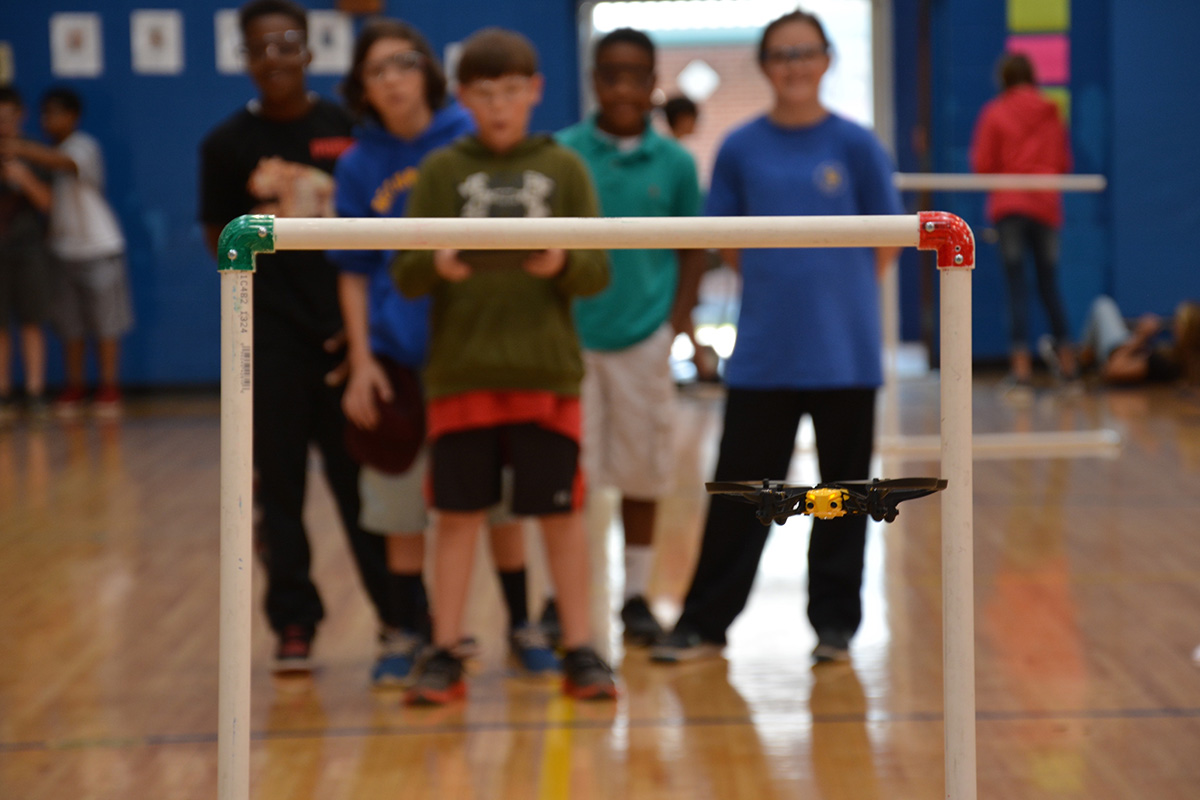 Kids flying a drone through a small hoop.