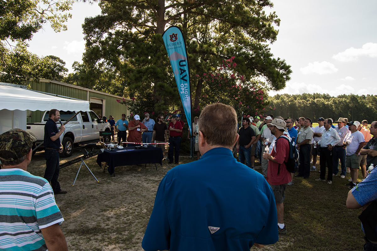 A group of people listening to a presentation outside.