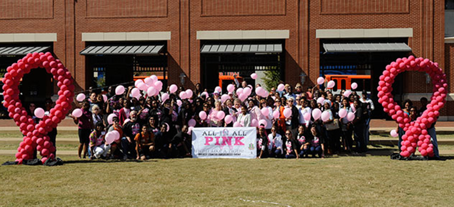 Group photo of attendees holding pink balloons and holding banner for all in all pink event
