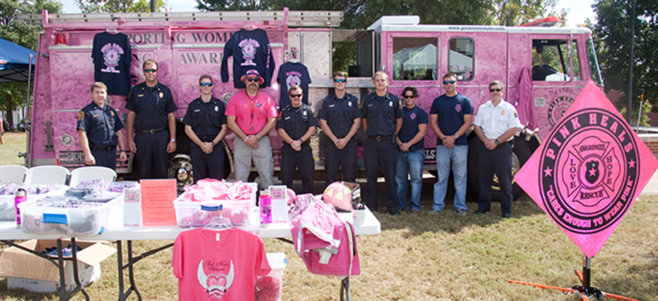 Firemen pose in front of pink firetruck
