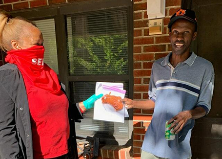 Man standing on front porch with Chruch of Highlands volunteer handing him a face mask